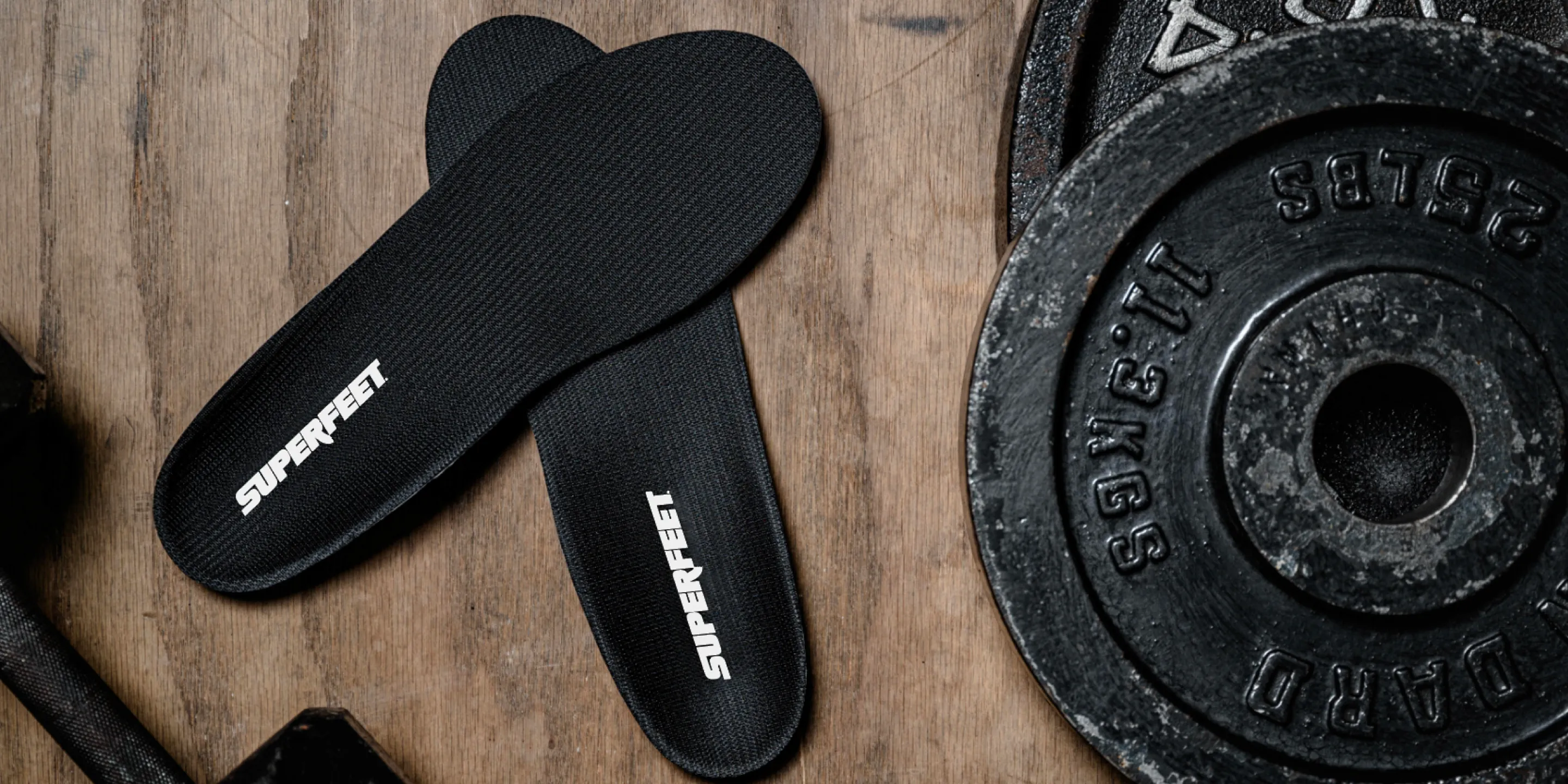 Black Superfeet insoles placed on wooden floor